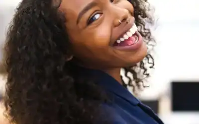 Smiling woman with curly hair showcasing a confident smile, representing dental care and confidence at Zen Dental in Enfield, CT.