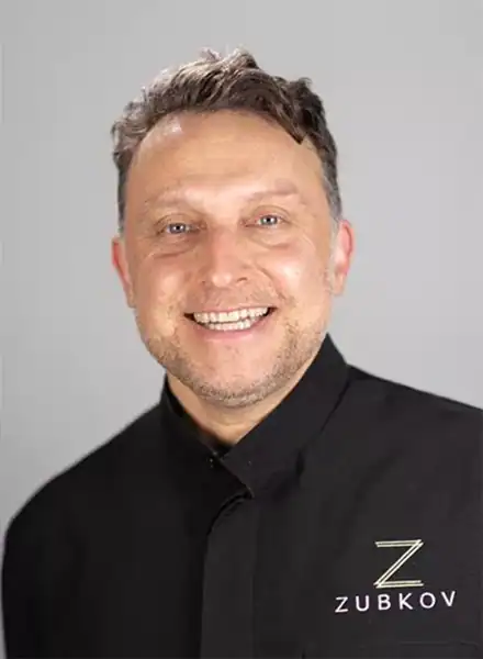 Dr. Alexander Zubkov, smiling dentist in black dental coat with Zubkov logo, representing Zen Dental practice in Enfield, CT.