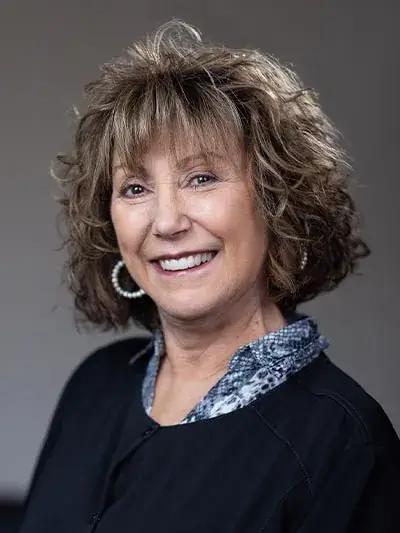Debbie, dental hygienist at Zen Dental, smiling with a friendly expression, wearing a black uniform and a patterned collar, showcasing her commitment to patient education and care.