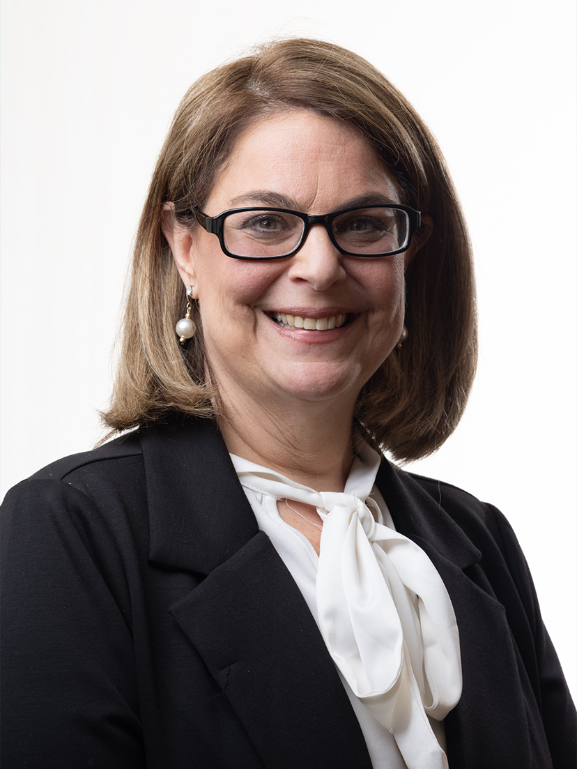 Jodie, office manager at Zen Dental, smiling in a professional outfit with glasses, showcasing her approachable demeanor in a bright setting.