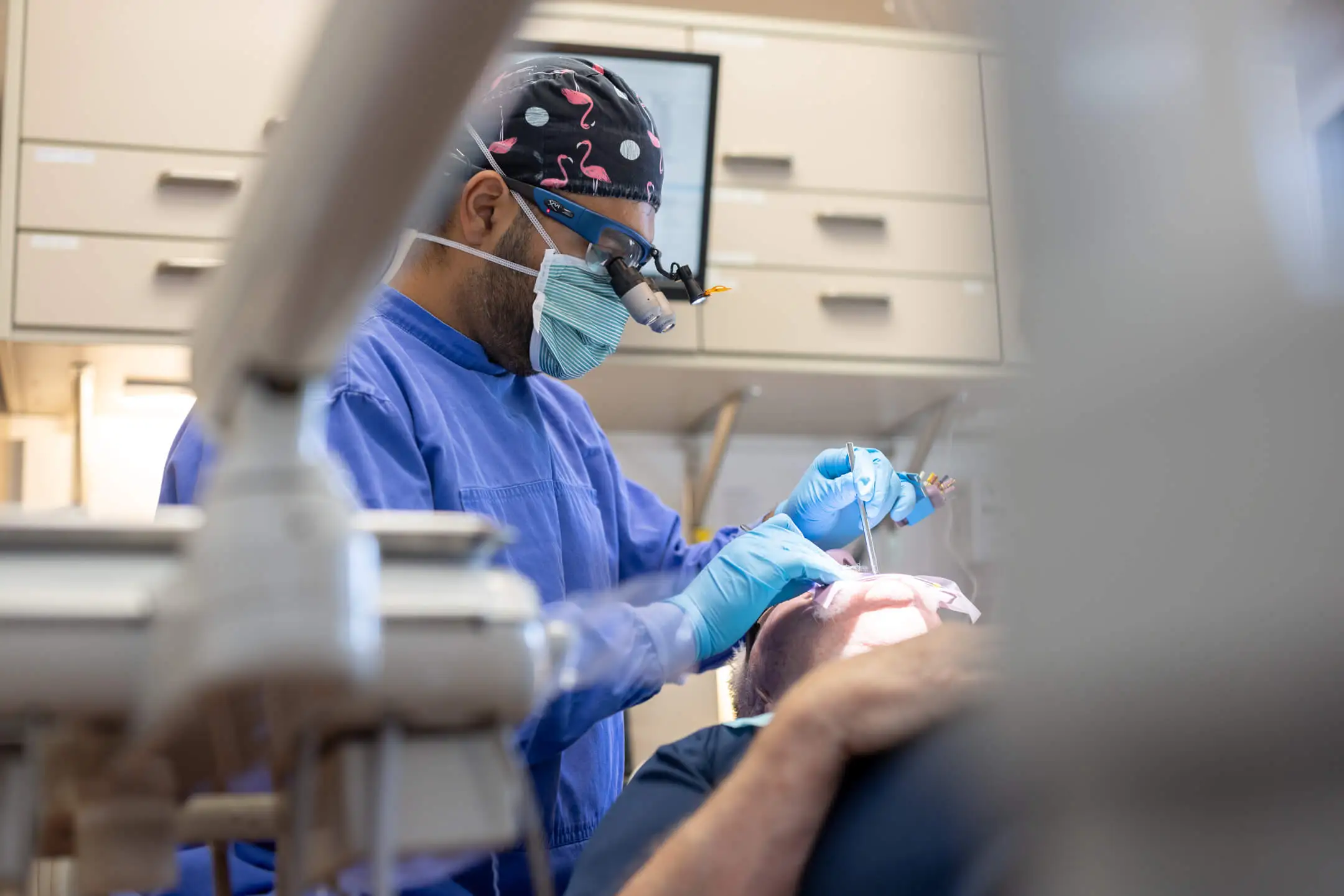 Dentist in blue scrubs and gloves performing restorative dental procedure on patient in dental chair, highlighting patient-first care at Zen Dental in Enfield, CT.